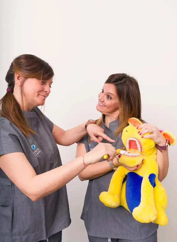 Due assistenti dello studio col pupazzo che usano per spiegare ai bambini come si lavano i denti